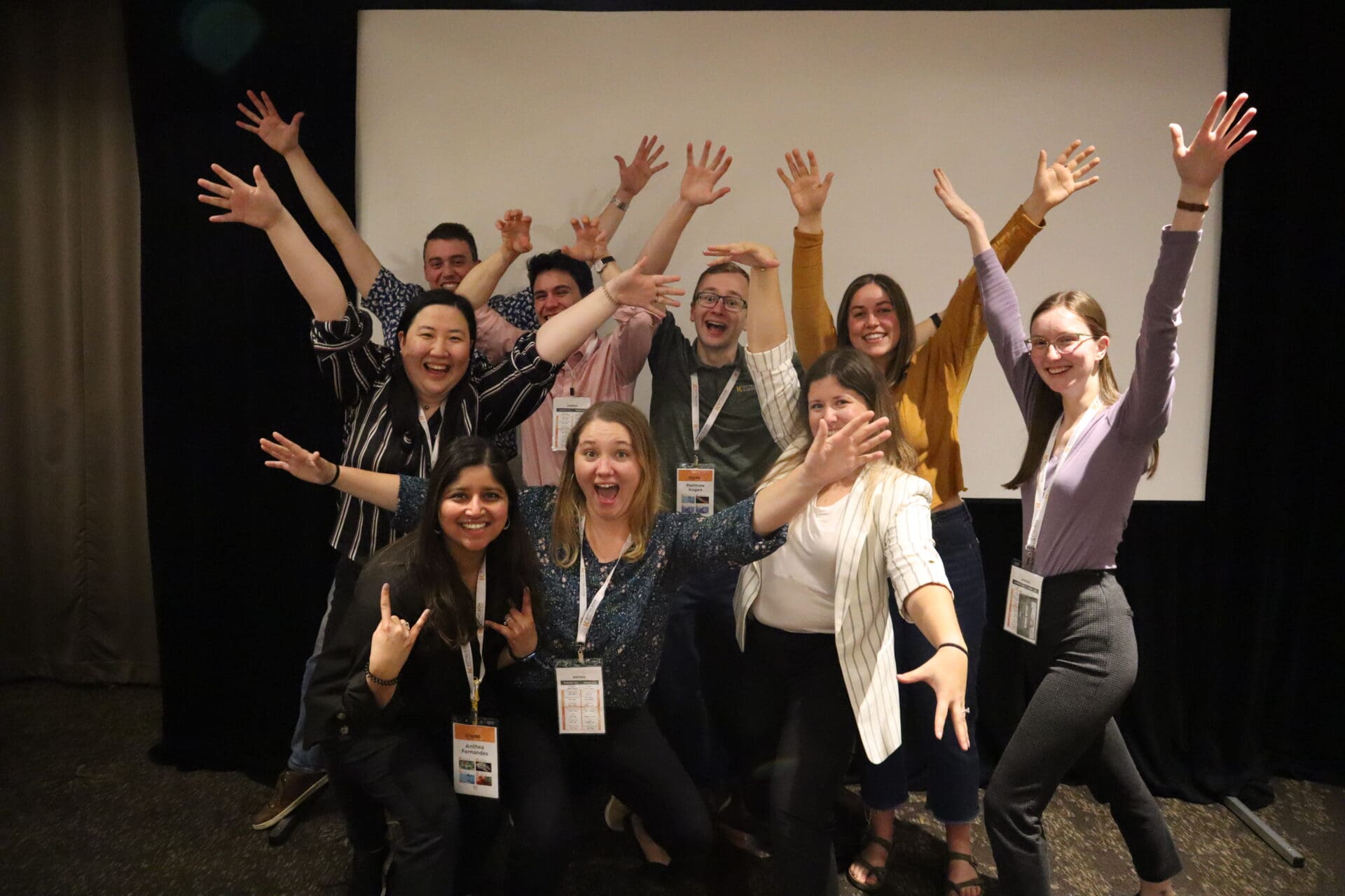 Group of people posing with their hands in the air.