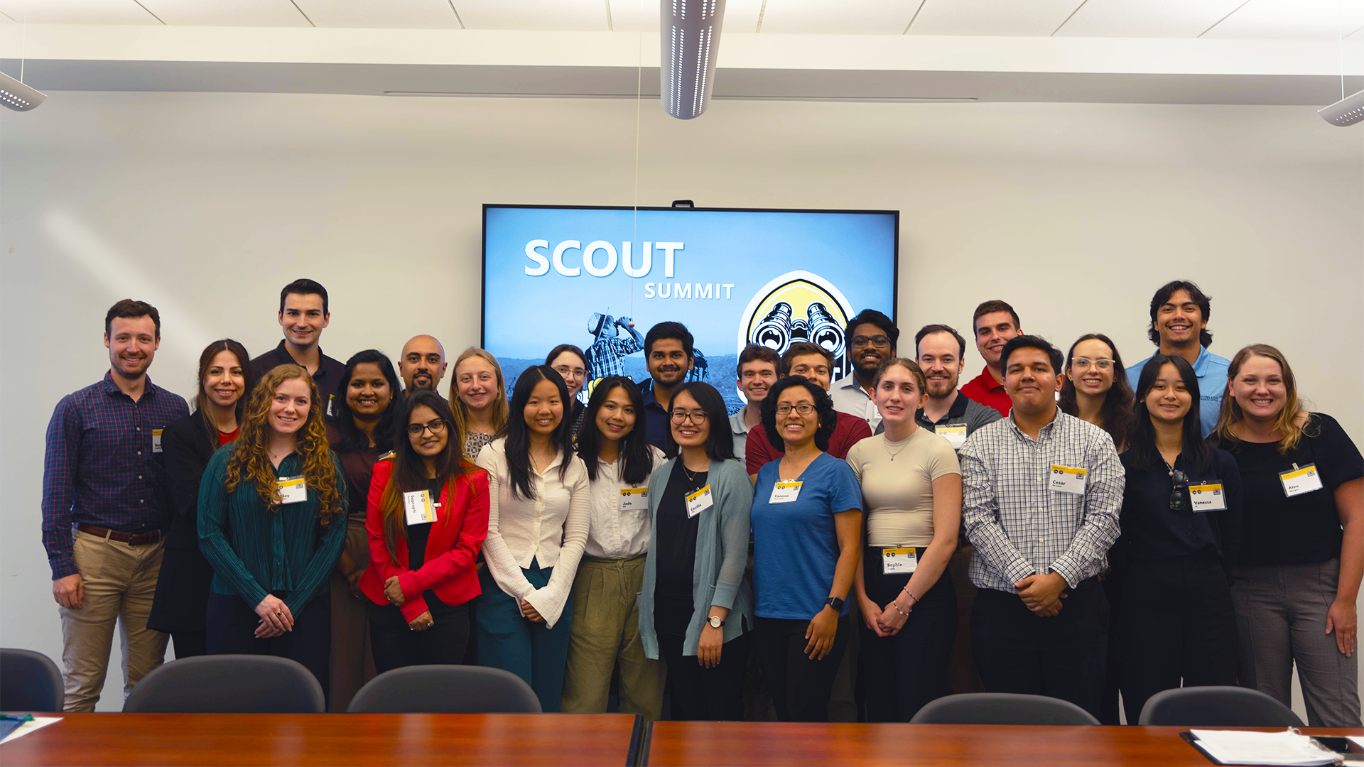 Image of group of people posing for the camera, in front of a sign that says SCOUT Summit.