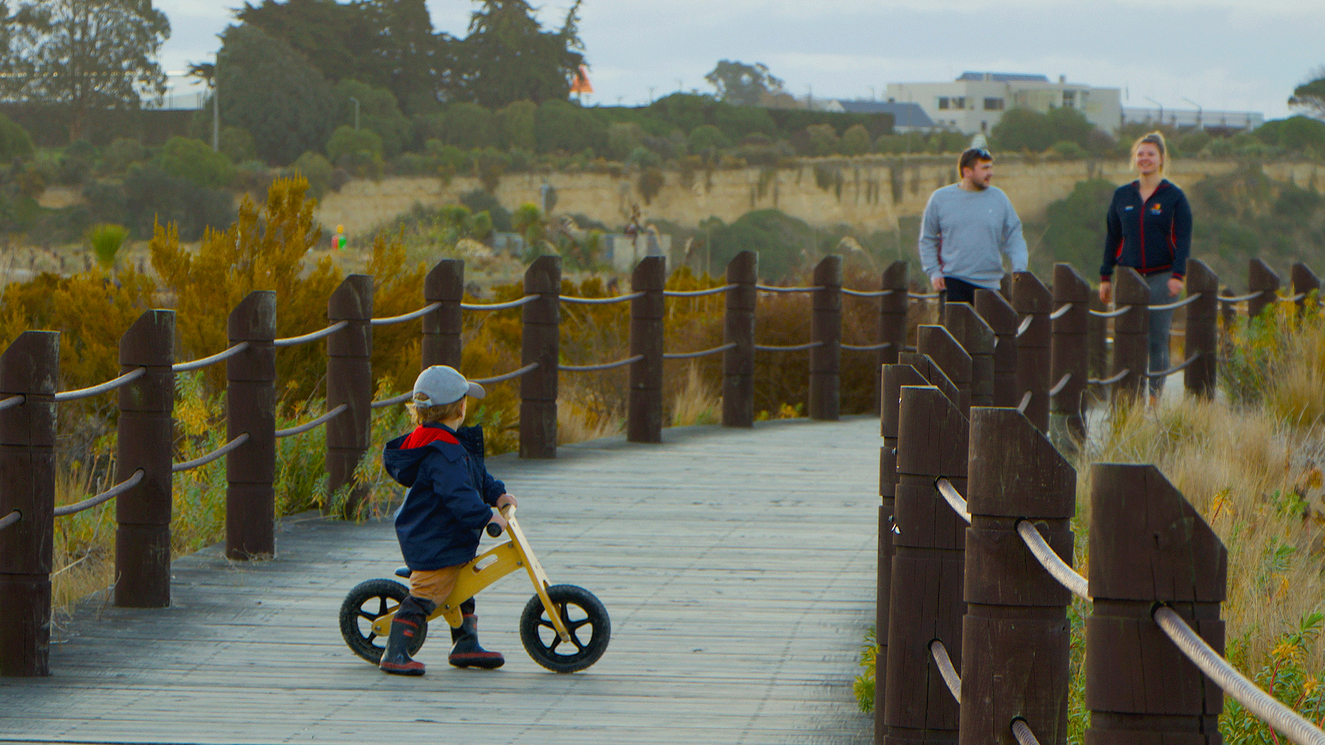 Little boy on a bike followed by his parents walking on a trail.