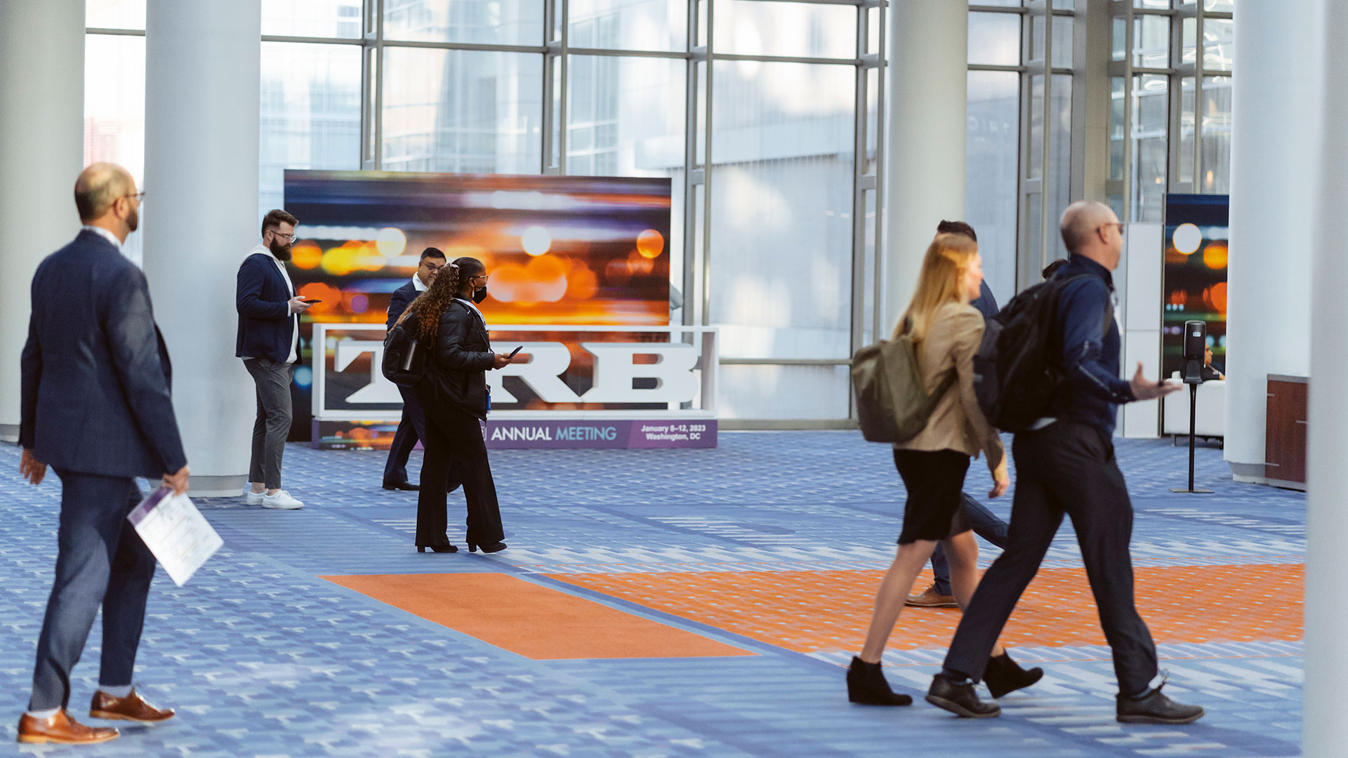 People walking across the Walter E. Washington Convention Center in front of a TRB 2023 sign