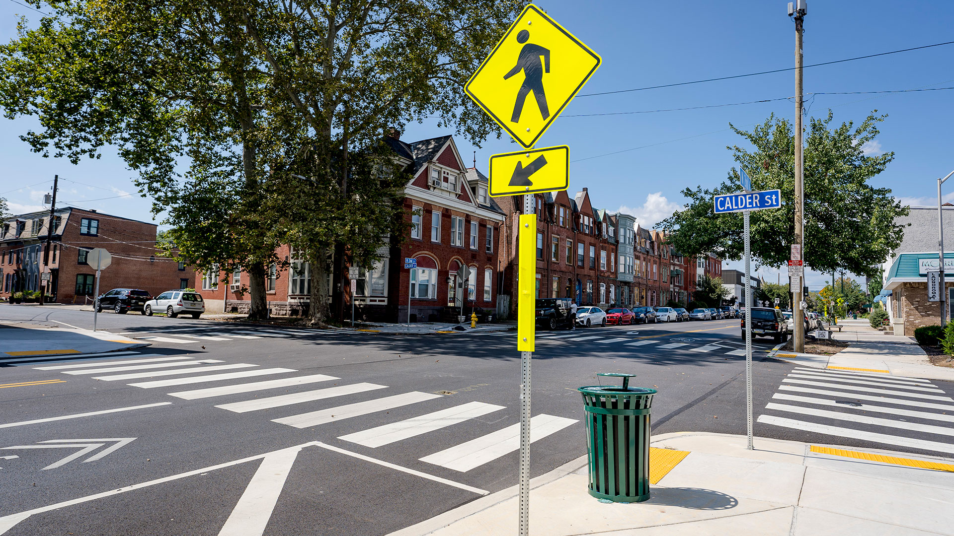 Pedestrian crossing sign with multimodal streetscape in the background