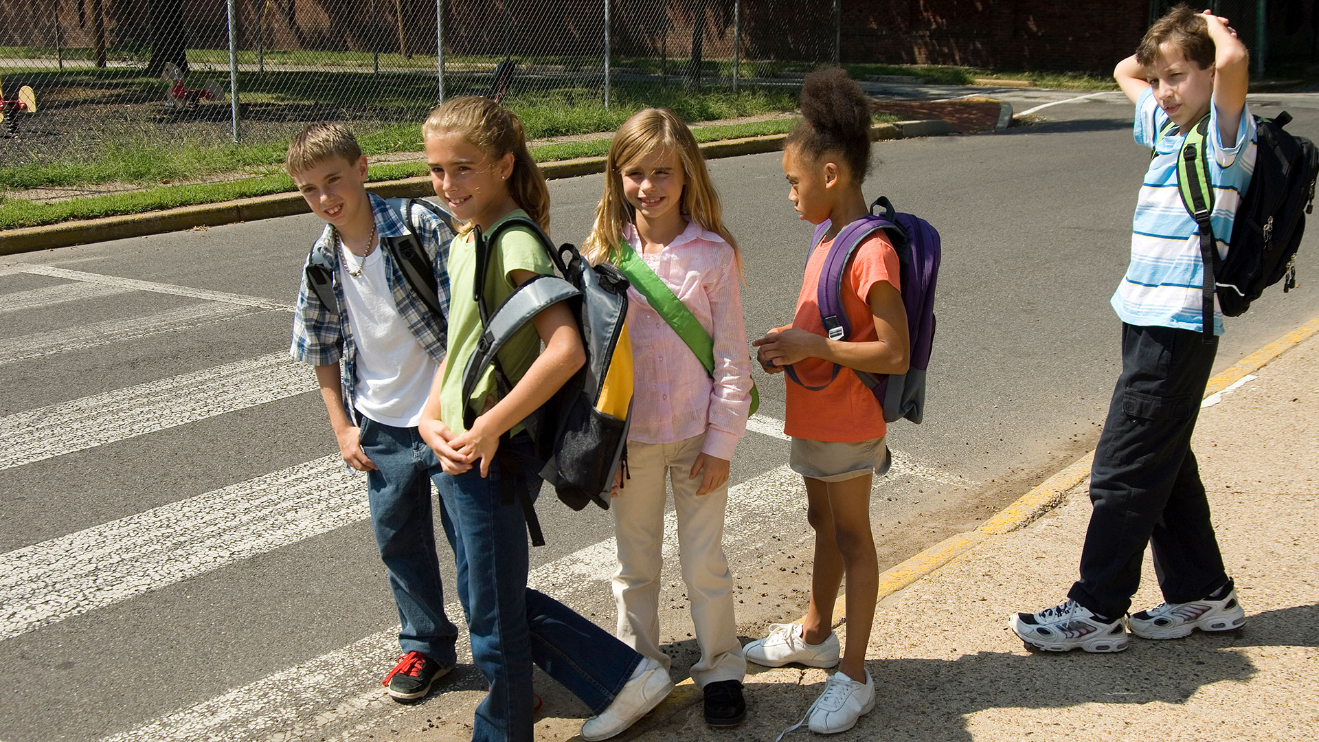 Group of children with backpacks waiting to cross the street