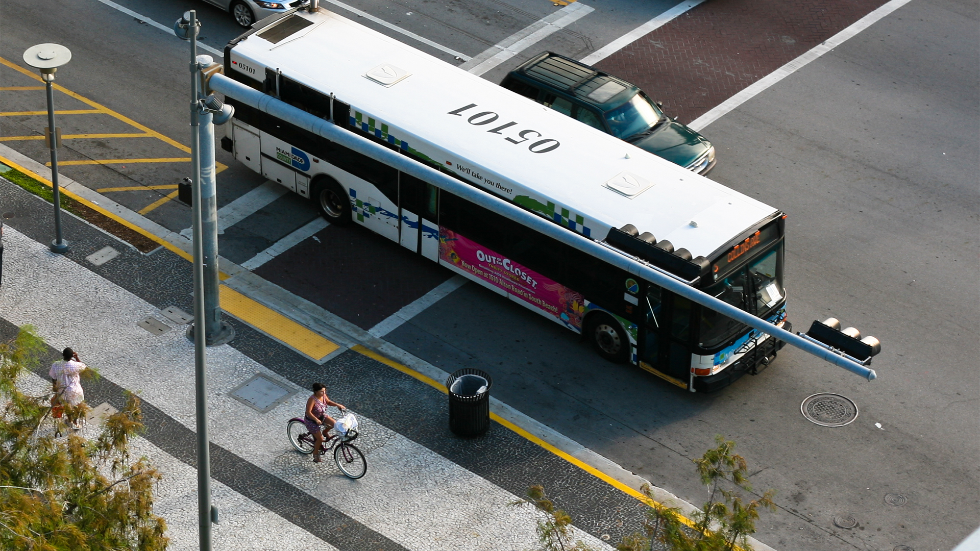 A road showcasing a protected bike lane, bus, and car riding next to each other.