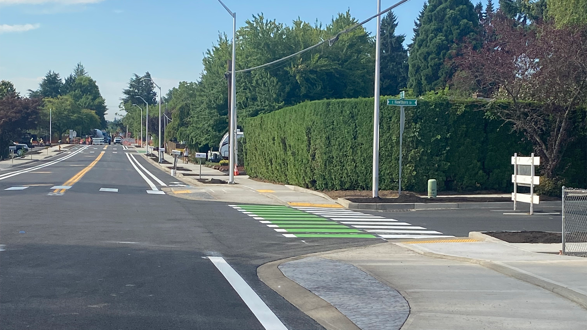 Road going off into the distance featuring a crosswalk and sidewalk.