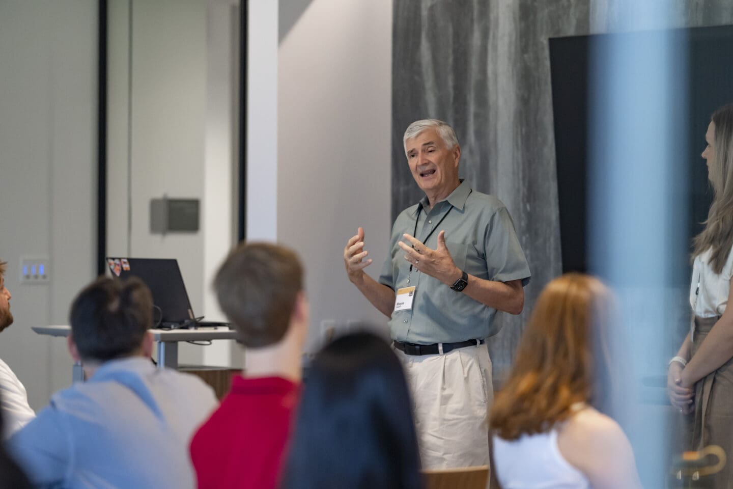 Man smiling, gesturing with hands while speaking to audience.