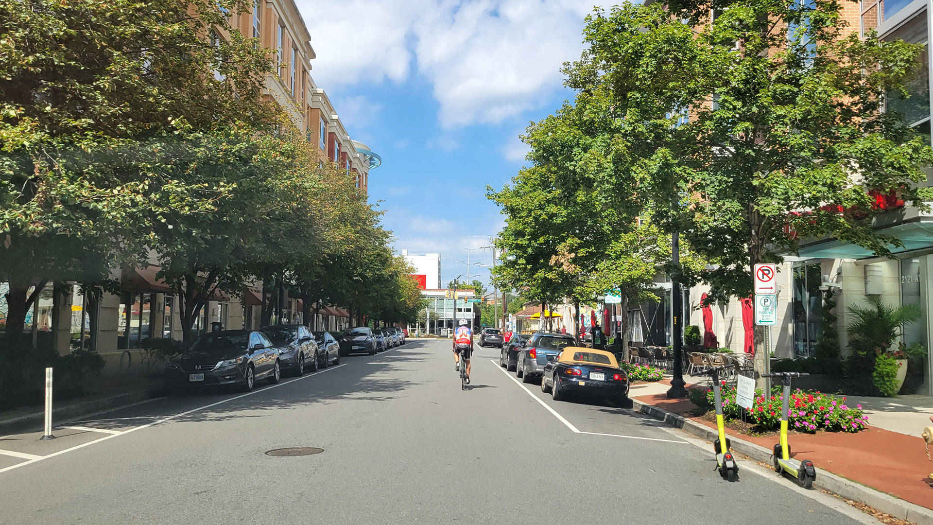 Bicyclist riding down a street with bikes and scooters