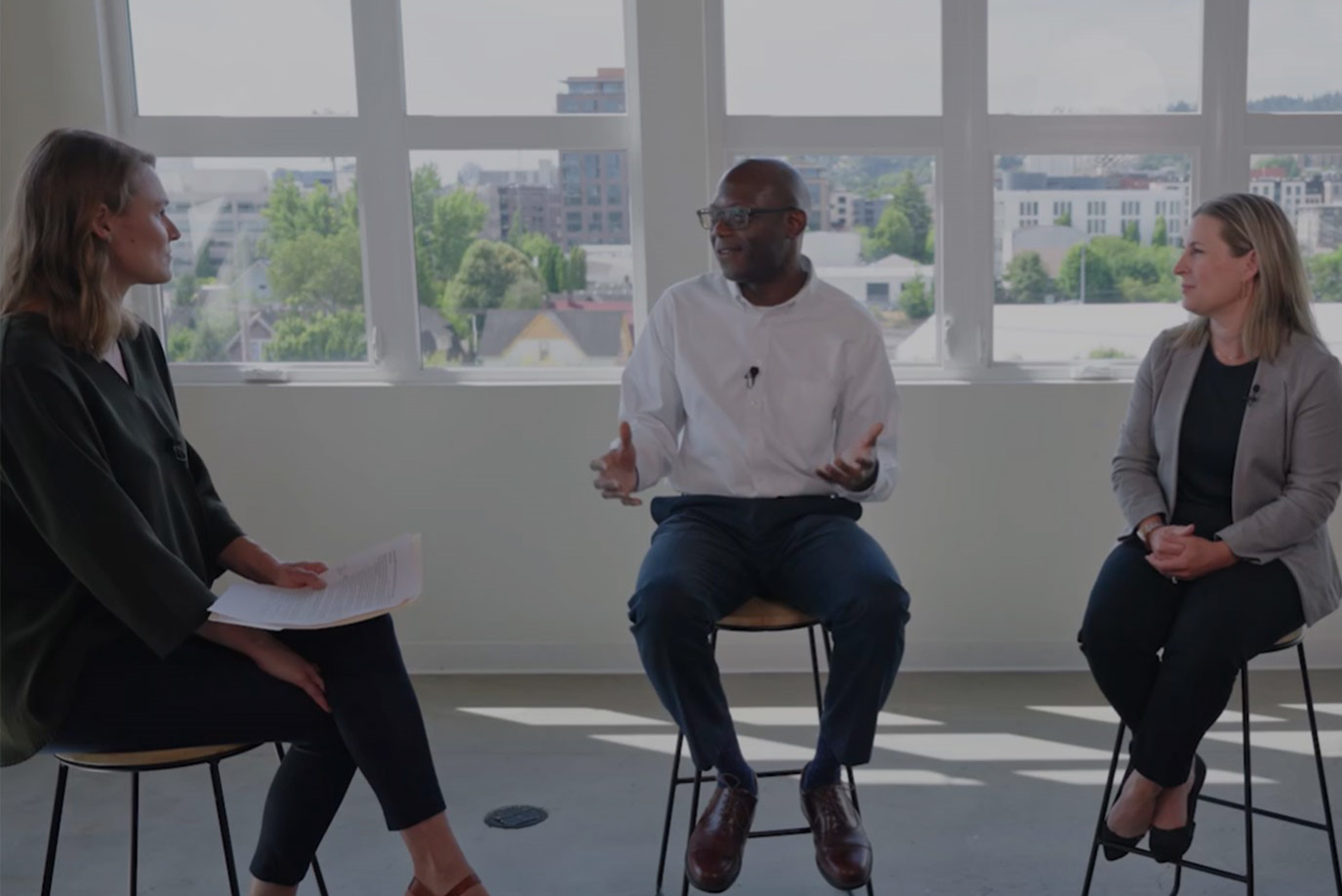 Three people sitting on stools having a conversation