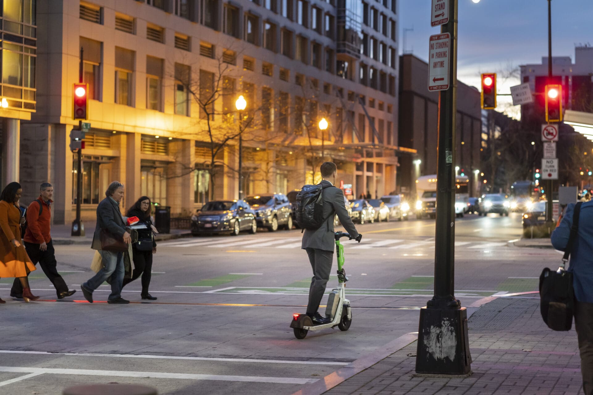 Intersection with pedestrians in the crosswalk and a scooter in the bike lane