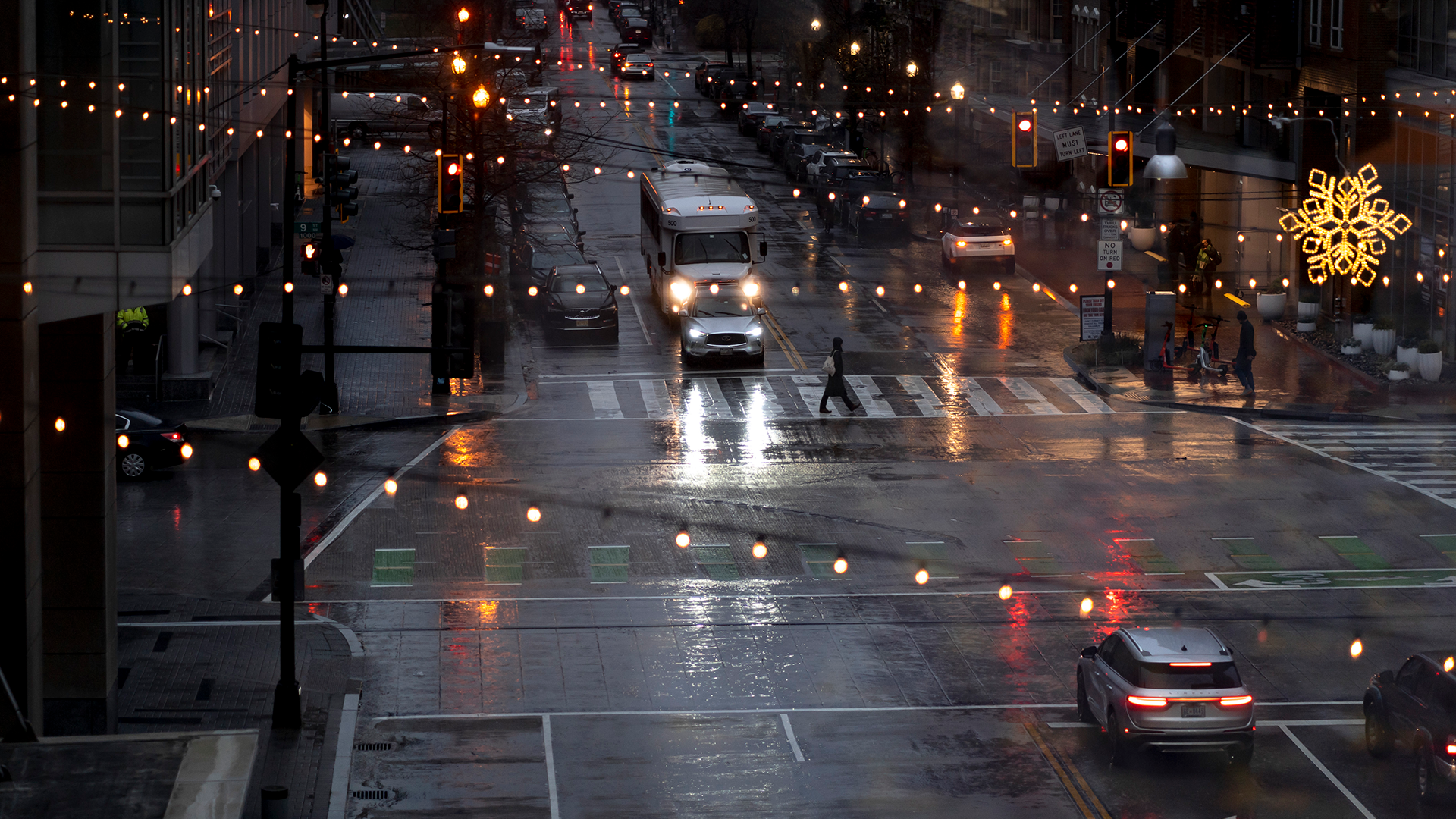 aerial view of dark, rainy intersection lit up by white Christmas lights