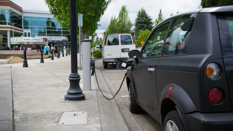 Gray car plugged into an EV charger on the street.