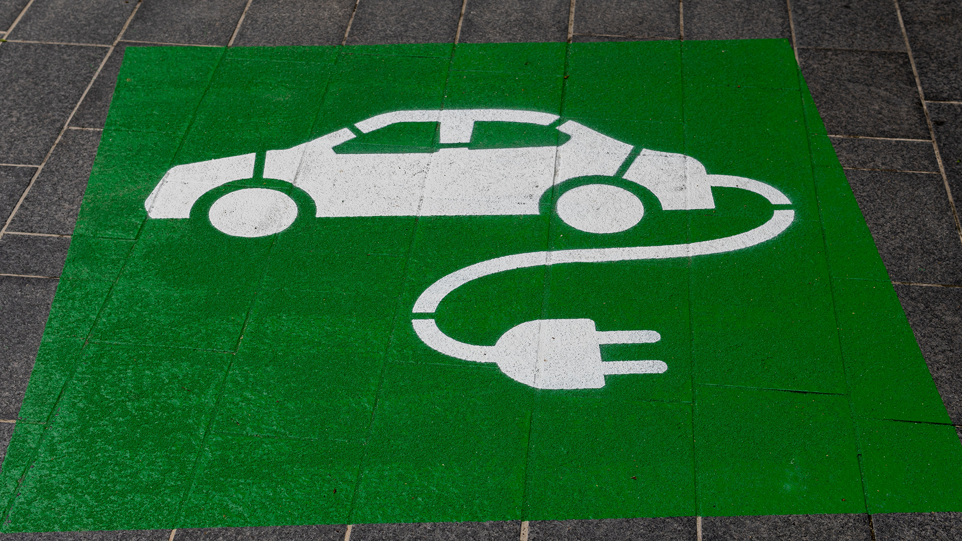 Sign on pavement: green background with white car.